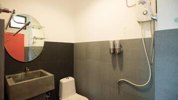 A bathroom with a toilet, a sink, a mirror, and a shower.