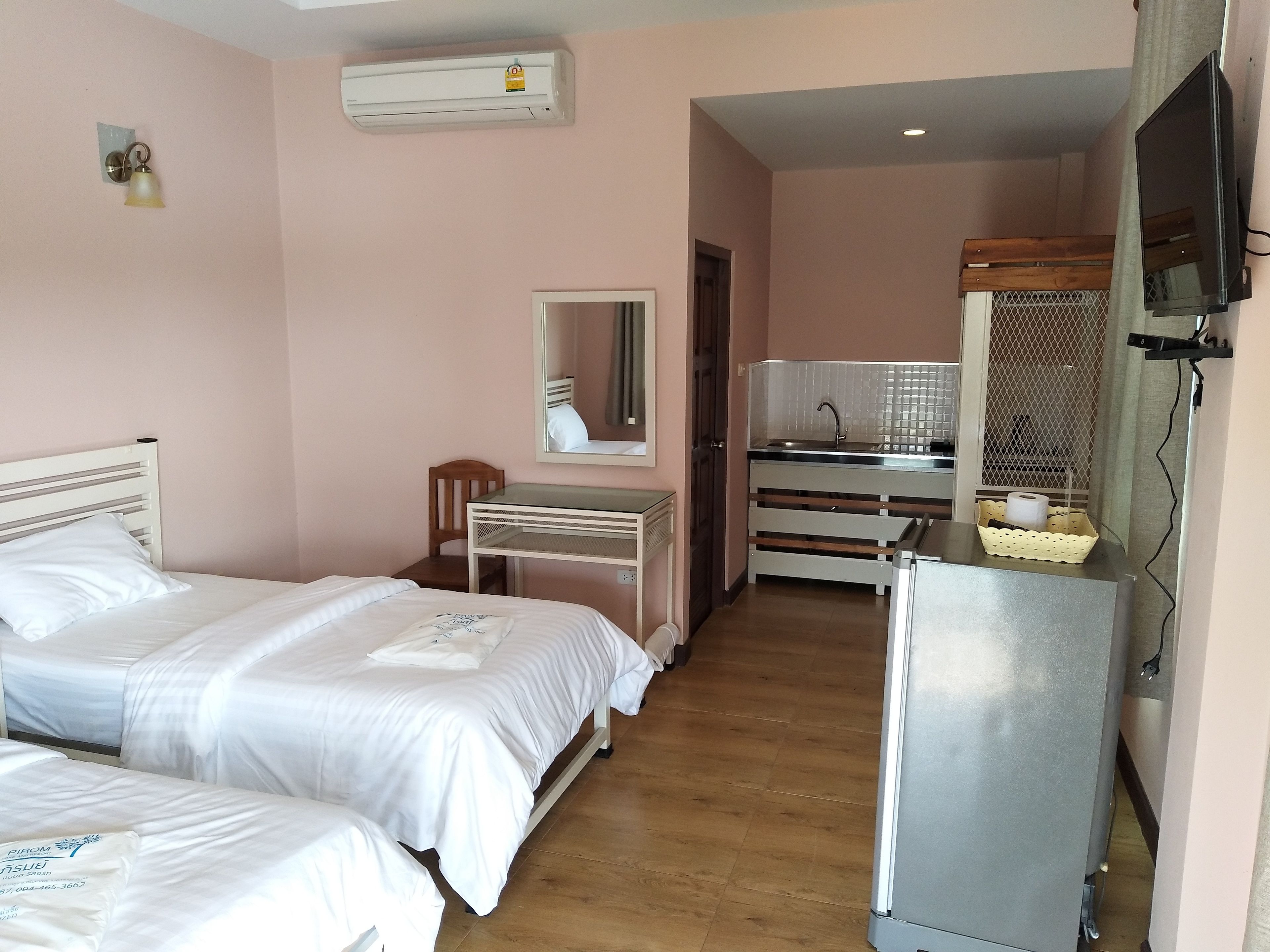 Une chambre d’hôtel avec deux lits, un bureau, un miroir, un lavabo et une télévision.