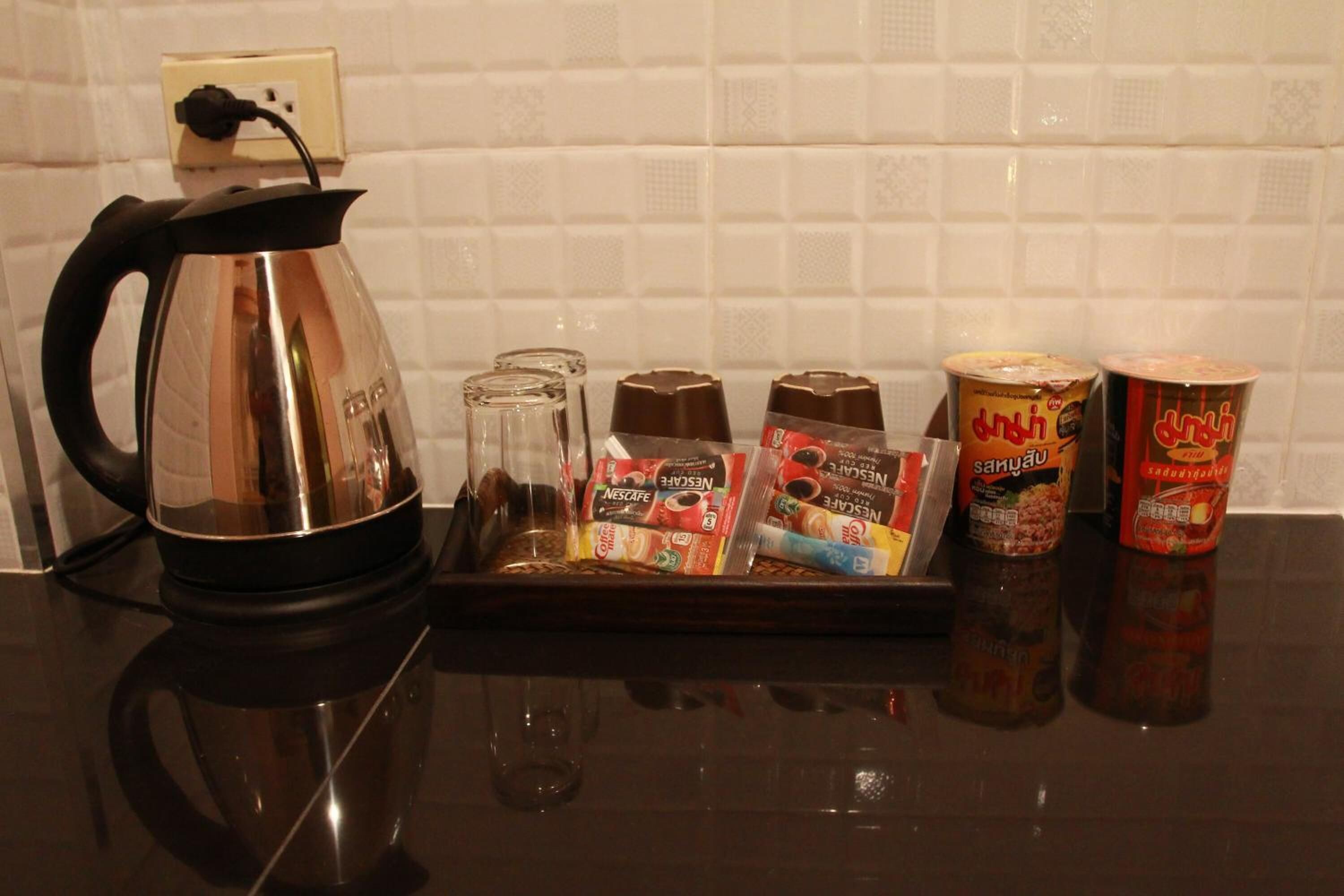 A kitchen counter with a kettle, coffee pods, and condiments.