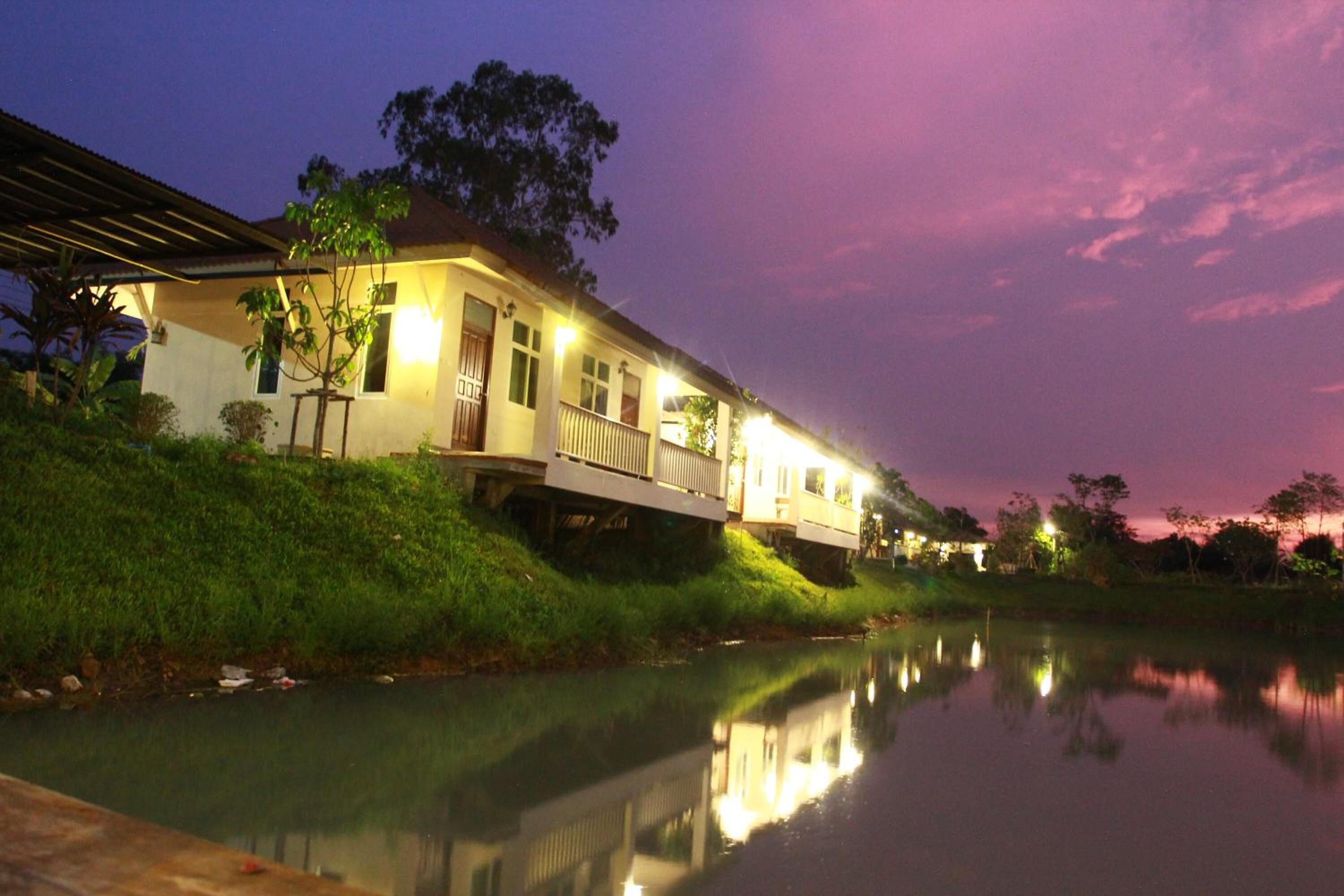A house with a balcony overlooking a calm body of water at dusk.