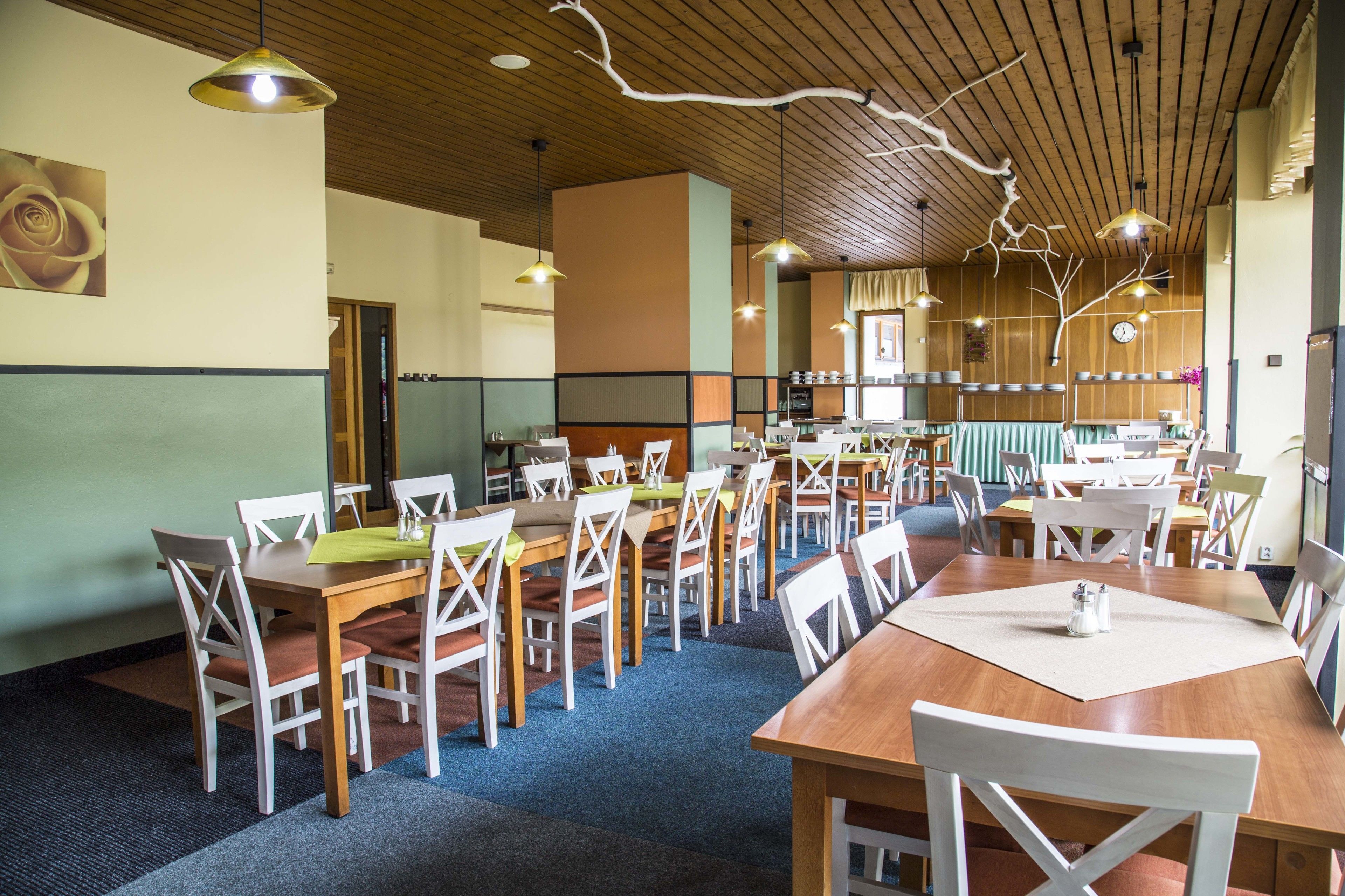 Un espace repas comprenant plusieurs tables et chaises, un plafond en bois et des luminaires suspendus.