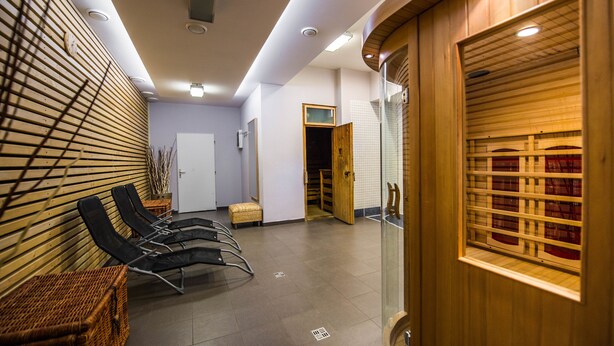 Un área de espera moderna con listones de madera, un mostrador de recepción y una puerta de cristal que da a una sala.