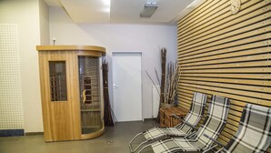 Un área de recepción con un mostrador de madera, una mampara de vidrio y una sala de espera con sillones lounge a rayas.