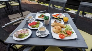 Una mesa dispuesta con diversos alimentos para el desayuno, como tostadas, huevos y fruta, junto con tazas de café y jugo.