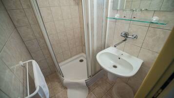 A small bathroom with a shower, toilet, and sink.