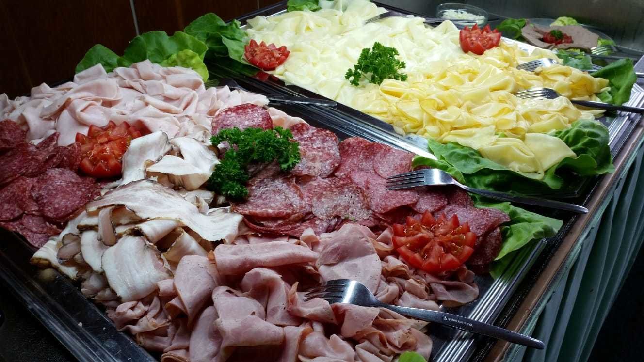 Een buffet met diverse vleessoorten, salades en bijgerechten.