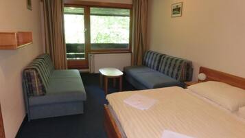 Une chambre d’hôtel avec un lit, deux canapés, une petite table et une fenêtre avec des rideaux.
