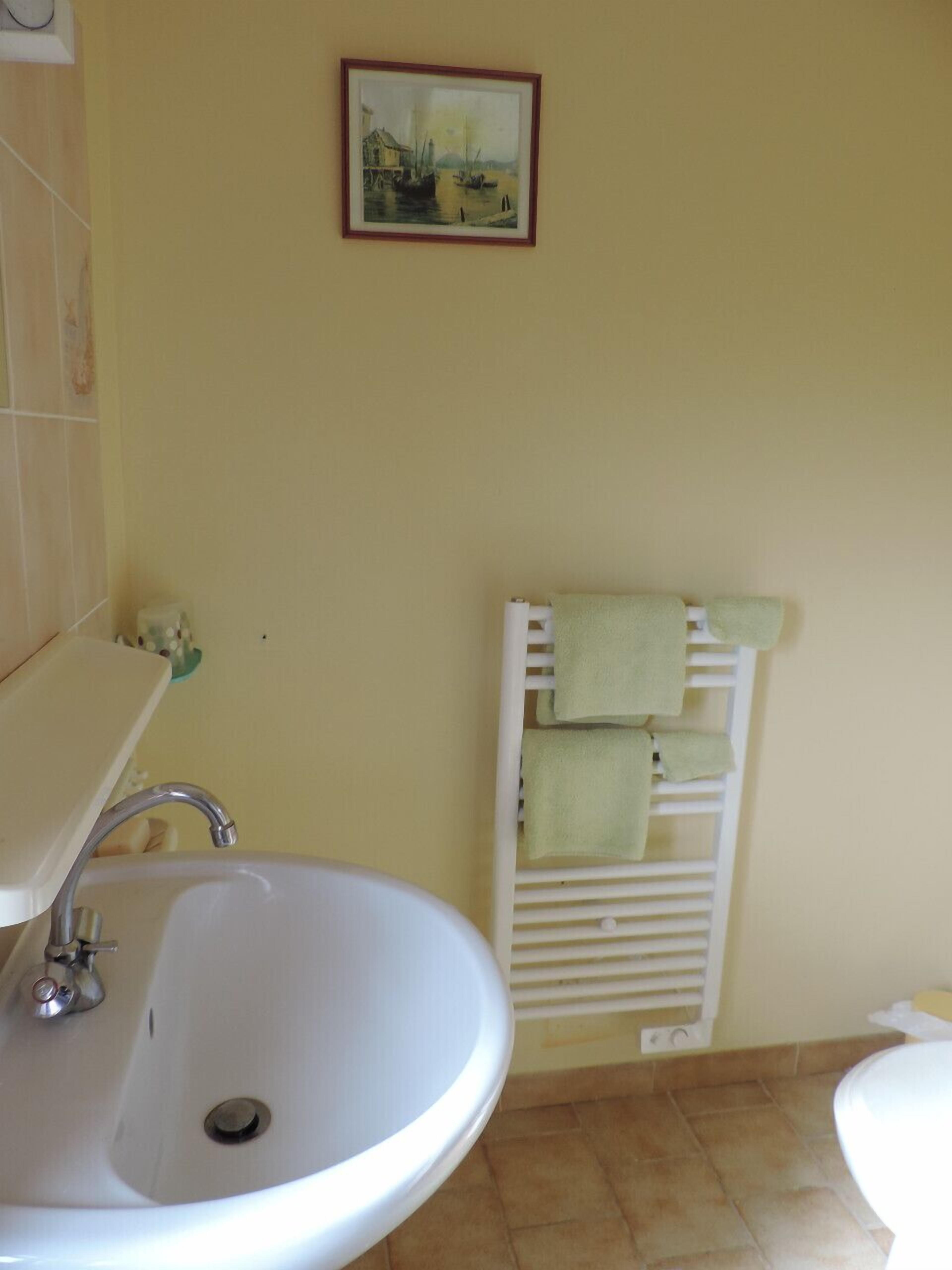 A bathroom with a sink, a toilet, and a towel rack with towels.