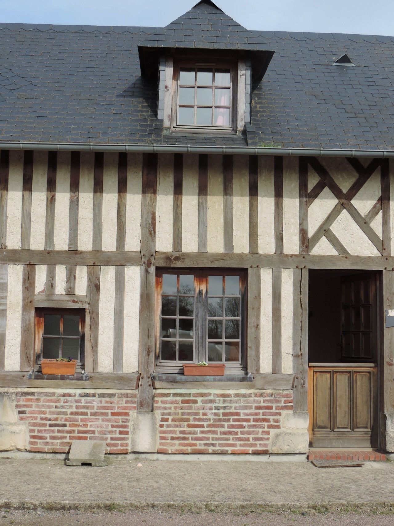 Il s’agit d’un bâtiment traditionnel à colombages, doté d’un toit à pignon, de deux fenêtres avec volets et d’une porte en bois.