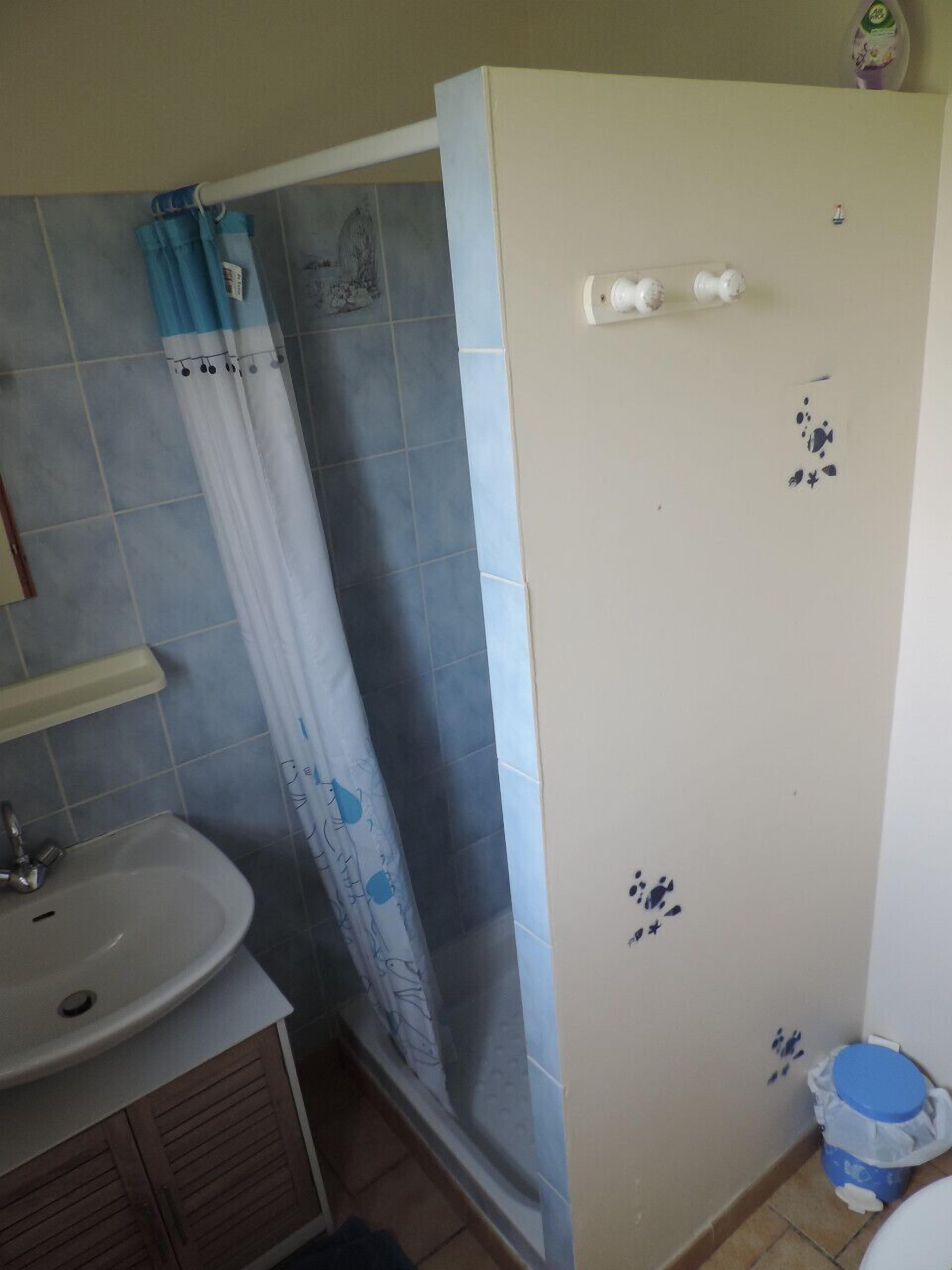 Ein Badezimmer mit Waschbecken, Dusche mit blauer und weißer Duschkabine und Toilette.