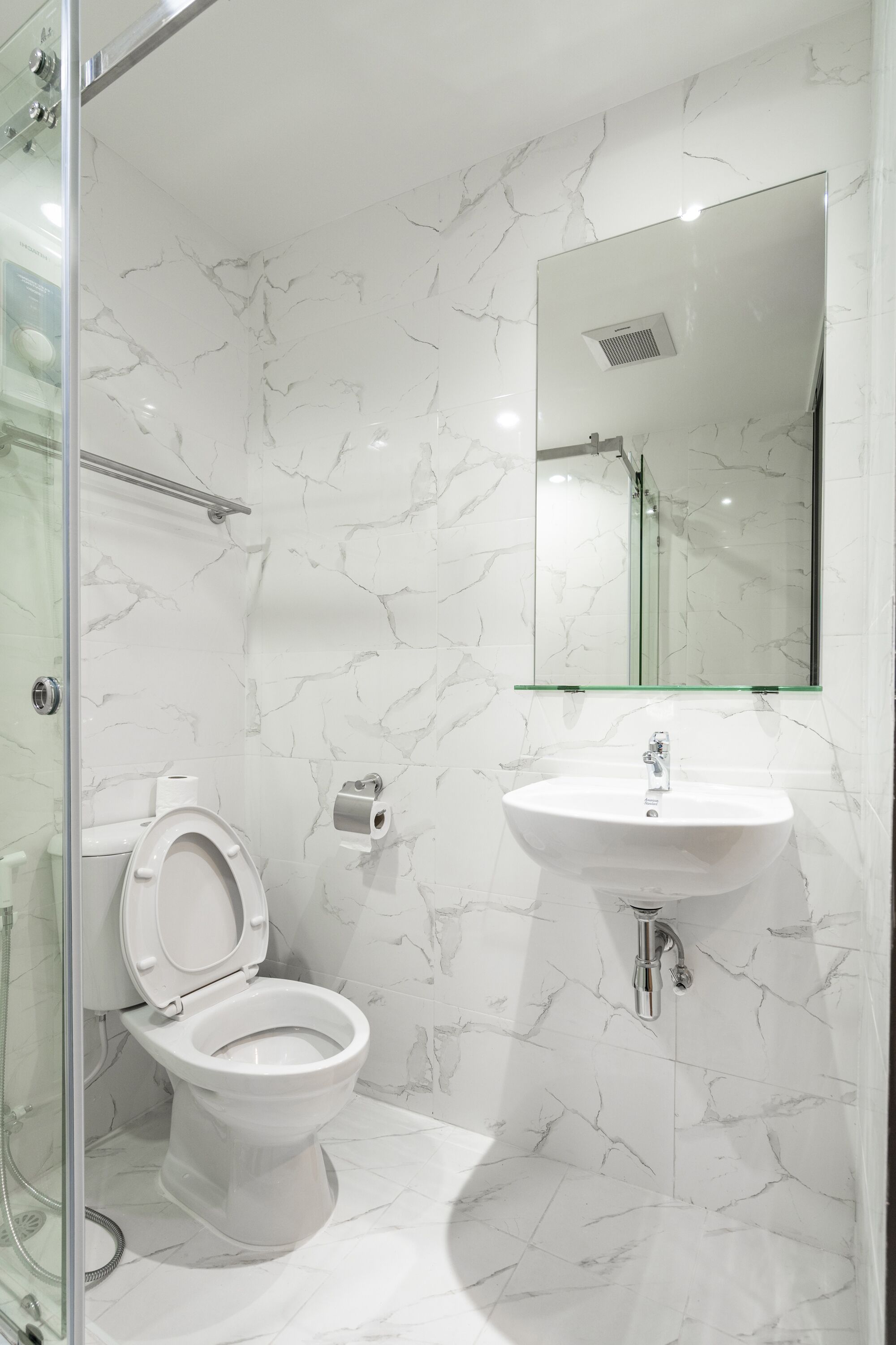 A bathroom with a toilet, sink, and glass shower enclosure.