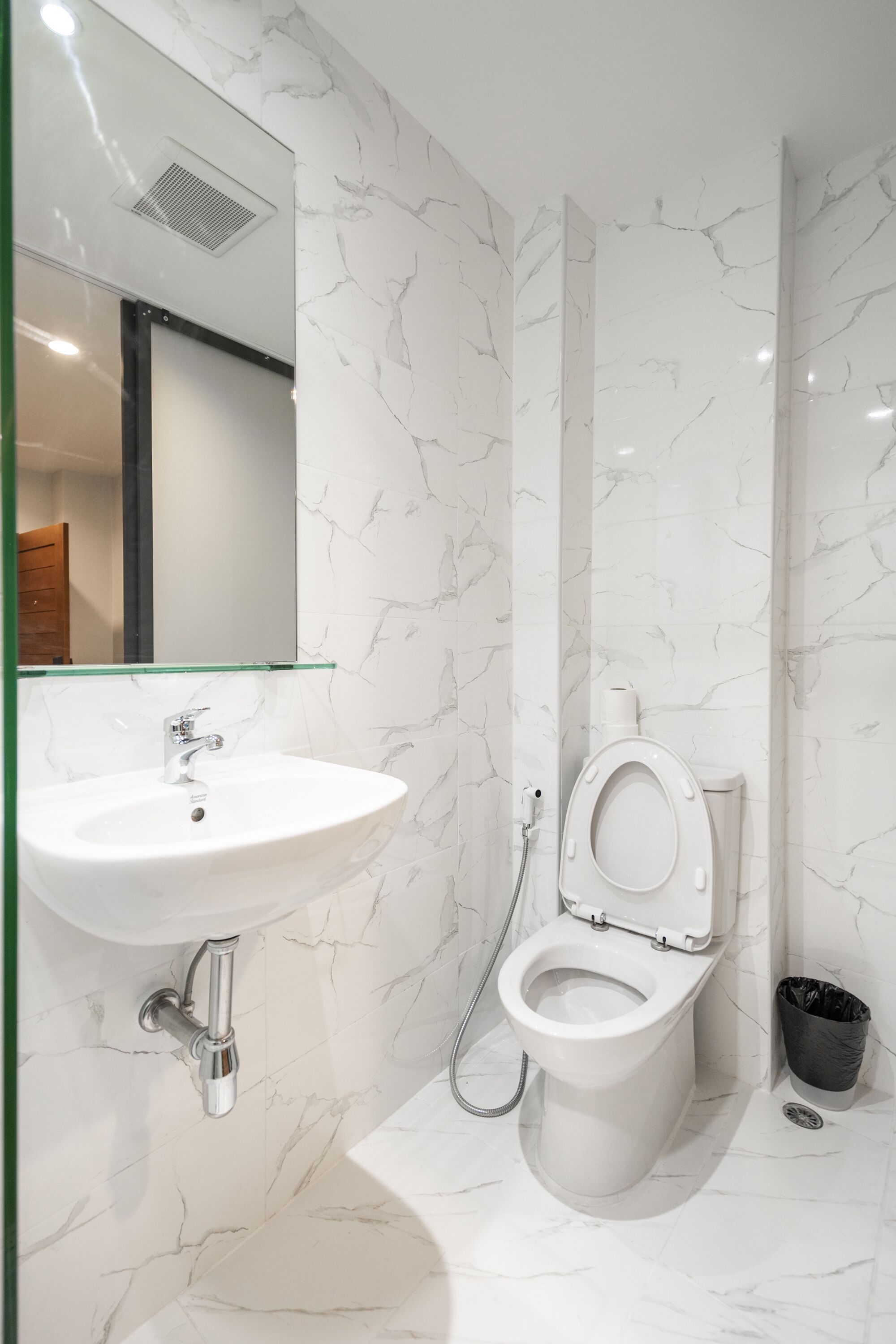 A bathroom with a white sink, toilet, and marble walls.