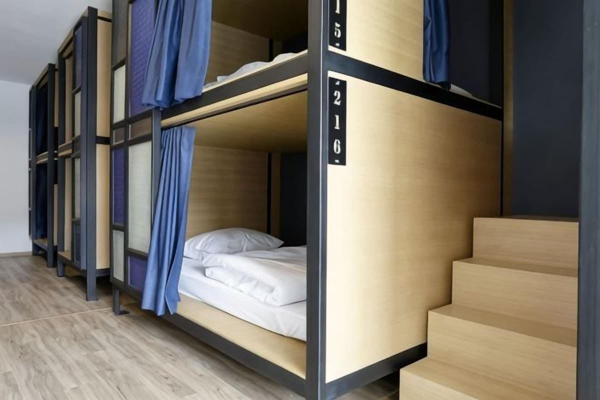 Eine Reihe von Etagenbetten mit Nummern an der Seite, Holzboden und eine Treppe.
