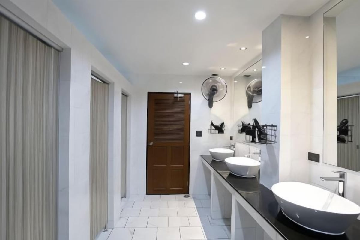 Ein modernes Badezimmer mit zwei Waschbecken, einem großen Spiegel und einem Deckenventilator.