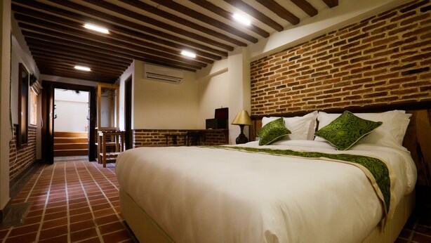 Una habitación de hotel con una cama grande, una pared de ladrillo y un techo de madera.
