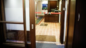 Entrada de un hotel con suelo de baldosas, un mostrador de recepción y una puerta de madera.