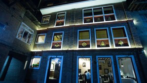 Un edificio de varios pisos con numerosas ventanas, algunas abiertas que dejan ver espacios interiores.