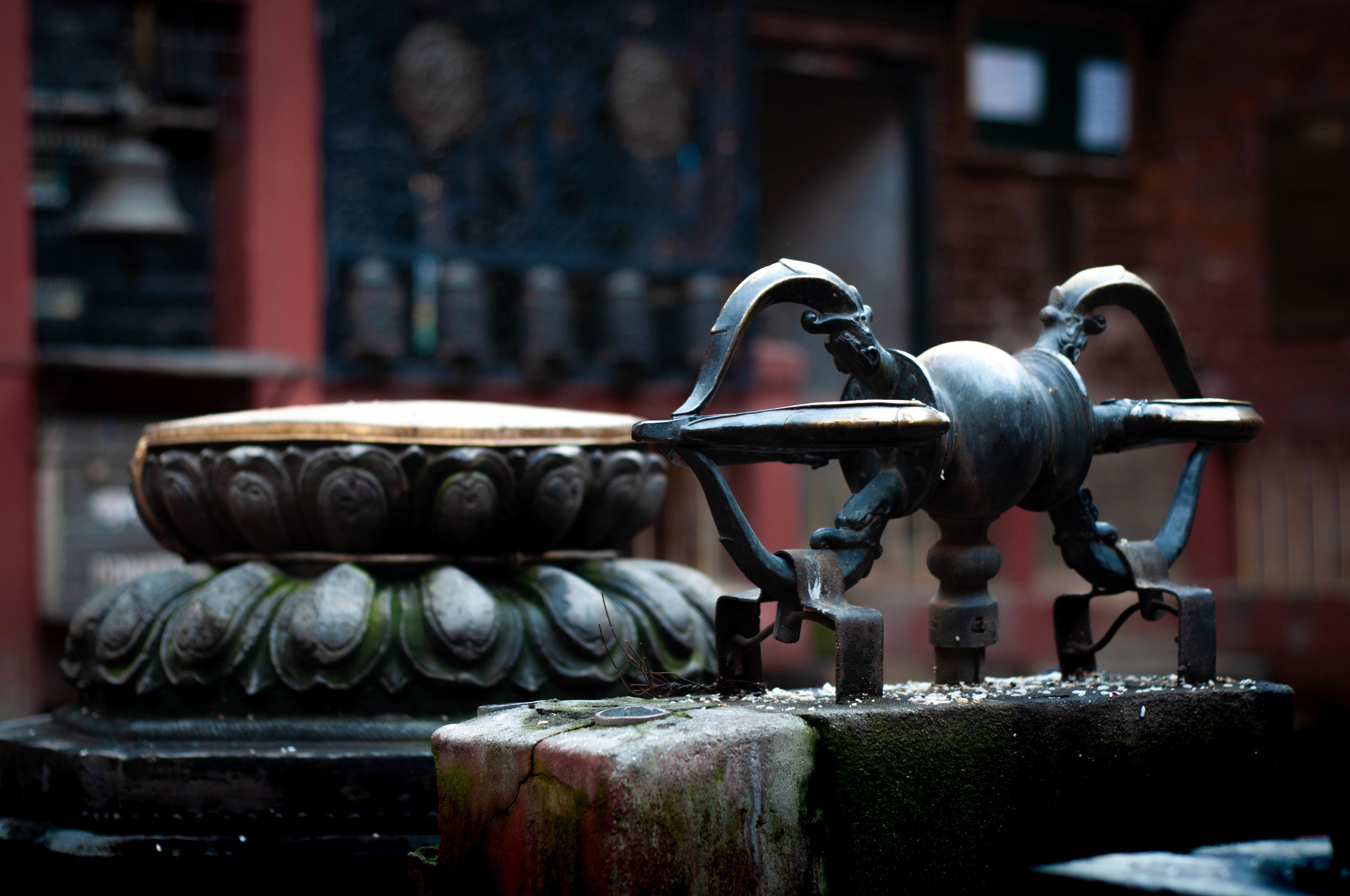 A metal sculpture of a mythical creature on a pedestal, with a decorative bowl in the background.