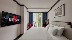 A hotel room with a large bed, a TV displaying the Netflix logo, a framed picture on the wall, and a view of the outdoors through the window. - The Passion Suite Hotel (Ho Chi Minh City)