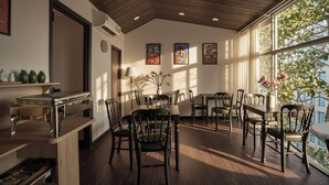 A dining area with wooden tables and chairs, a kitchen counter, and artwork on the walls. - The Passion Suite Hotel (Ho Chi Minh City)