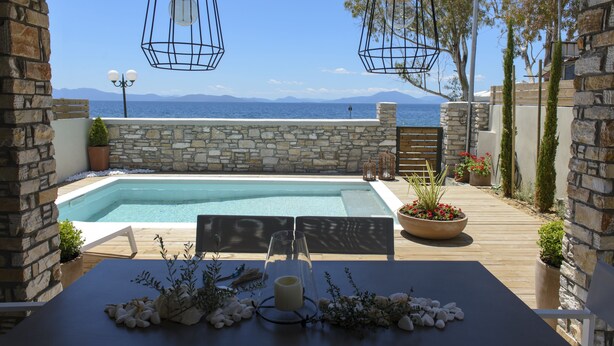 Un área junto a la piscina con muros de piedra, una terraza de madera y faroles colgantes.