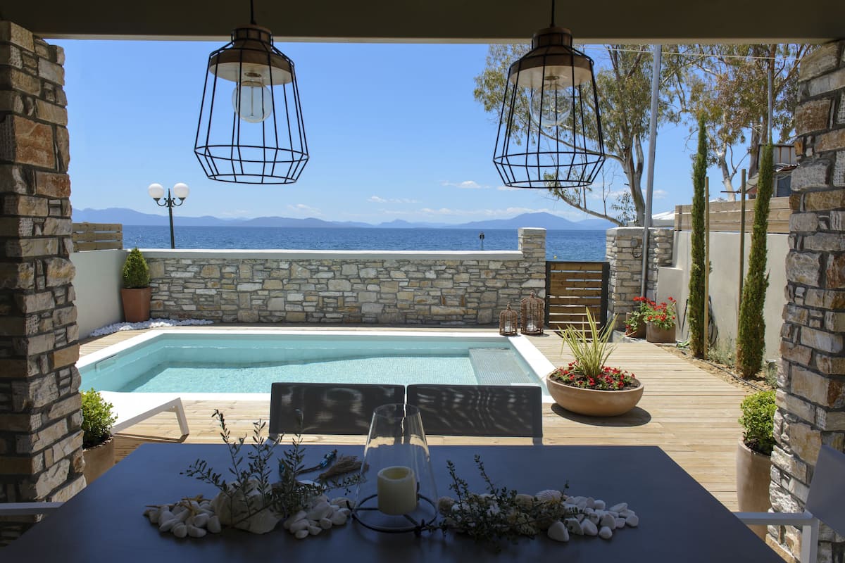 Un área junto a la piscina con muros de piedra, una terraza de madera y faroles colgantes.