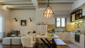 Una cocina moderna con comedor, que incluye una mesa de madera, sillas y una lámpara colgante.