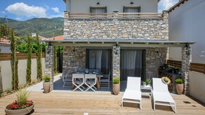 Un edificio de piedra con un patio, mobiliario exterior y vistas a las montañas.