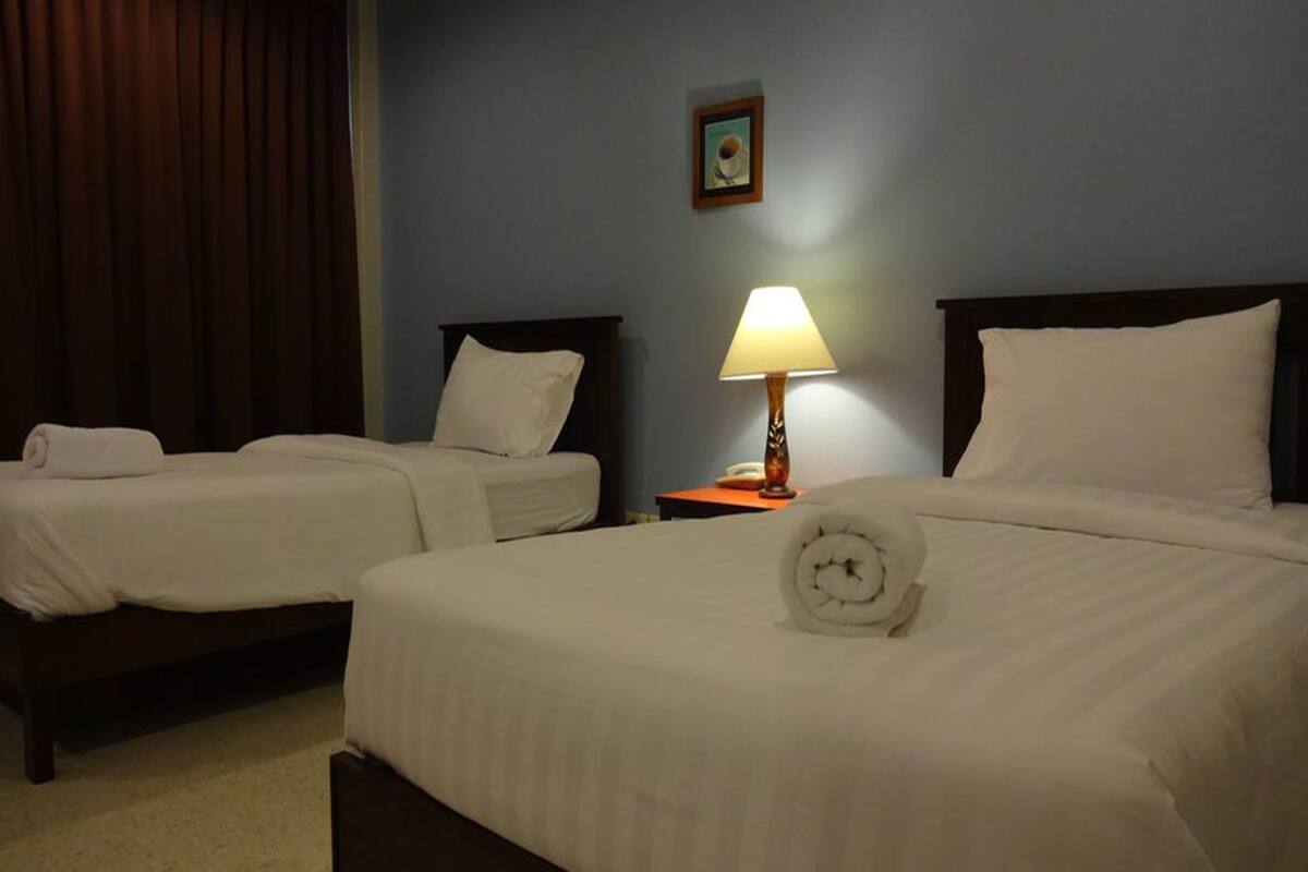 Una habitación de hotel con dos camas individuales, una mesita de noche con lámpara y un cuadro en la pared.