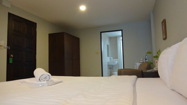Una habitación de hotel con cama, una silla, escritorio y un espejo.