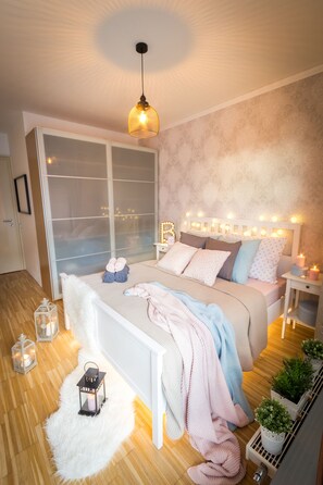 Quarto moderno com cama grande, mesas de cabeceira, guarda-roupa e iluminação decorativa.