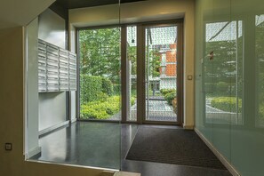 Um interior moderno com uma porta de correr de vidro que dá para um jardim, um armário de metal e um tapete preto na entrada.