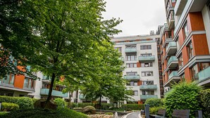 A residential building with multiple balconies, a landscaped garden with a water feature, and a paved pathway. - Luxury apartment River Diamond residence (Prague)