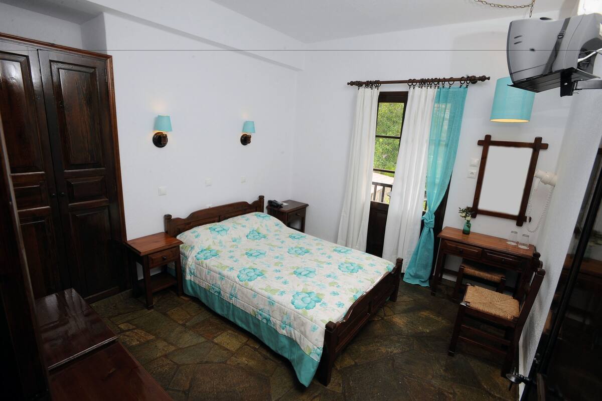 Un dormitorio con cama, mesitas de noche, cómoda, espejo y ventana con cortinas.
