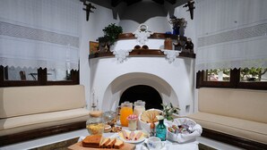A breakfast setup with a table, seating, and a fireplace. - Elli Hotel (Skopelos)