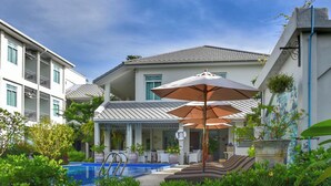 Un hotel con piscina, mobiliario exterior y una zona cubierta con sombrillas.