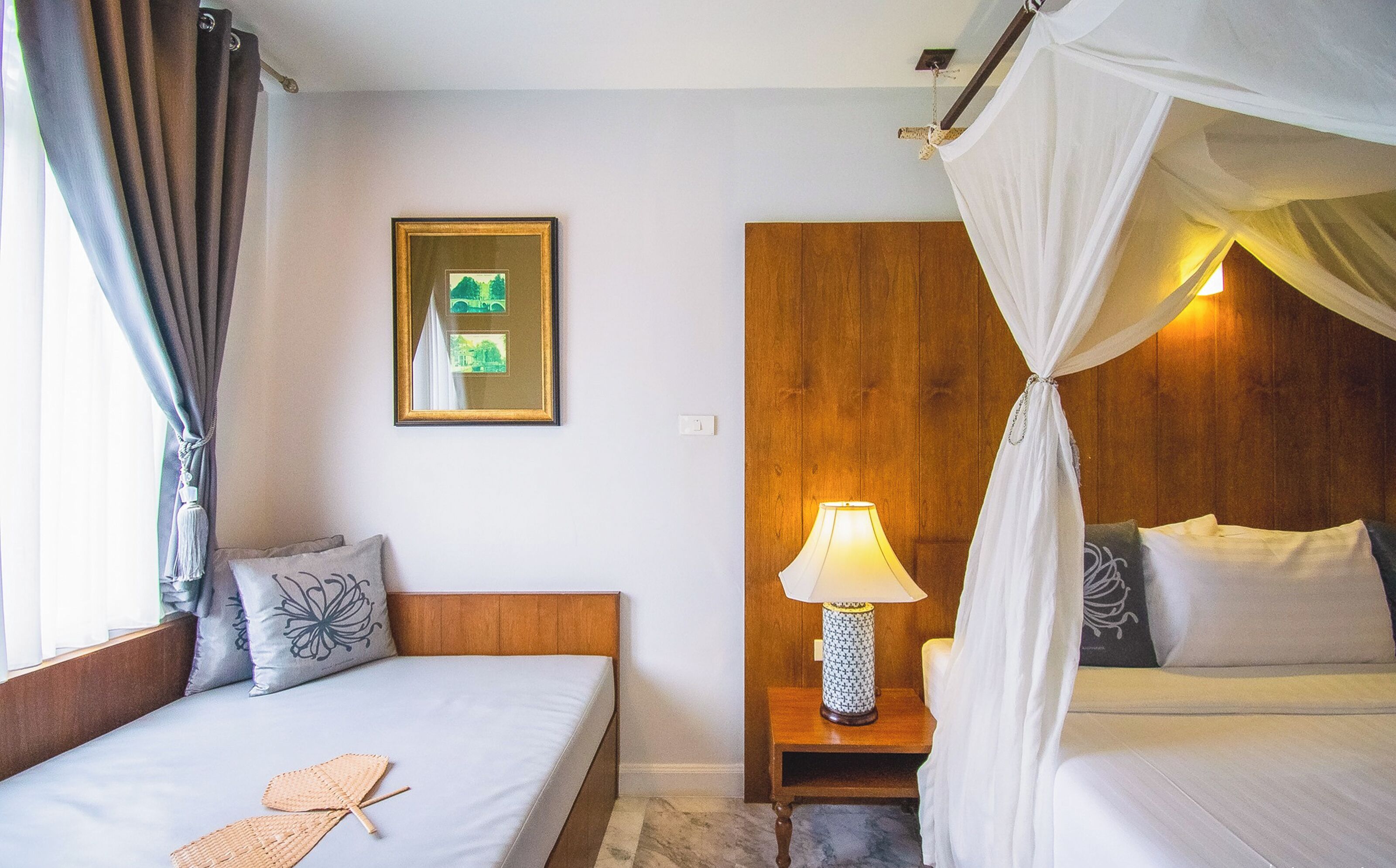 Une chambre d’hôtel avec un lit, une table de chevet avec une lampe, un tableau au mur et un lit à baldaquin.