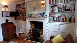 Una sala de estar acogedora con chimenea, estanterías, televisor y sofá de cuero.