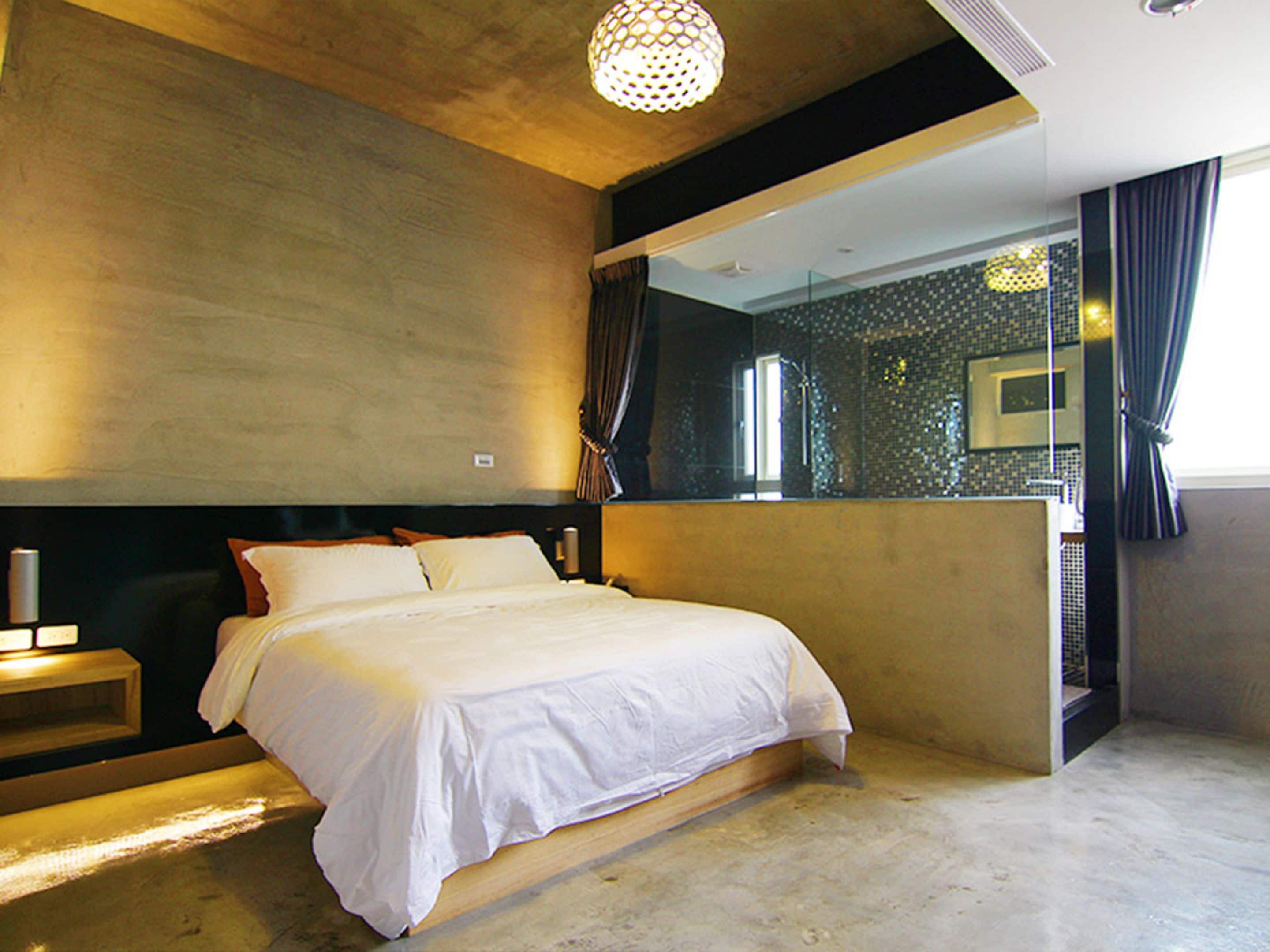 A modern bedroom with a large bed, a nightstand, a mirror, and a ceiling light fixture.