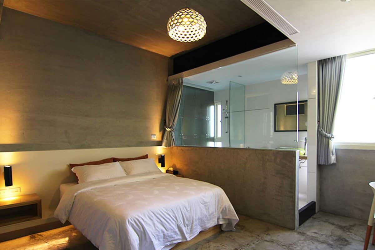 Un dormitorio moderno con una cama grande, lámparas de noche, un espejo y vistas a un baño.