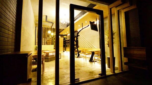 An interior space with a staircase leading to a higher level, a dining area with tables and chairs, and a visible trash bin. - Hotian Inn (Donggang)
