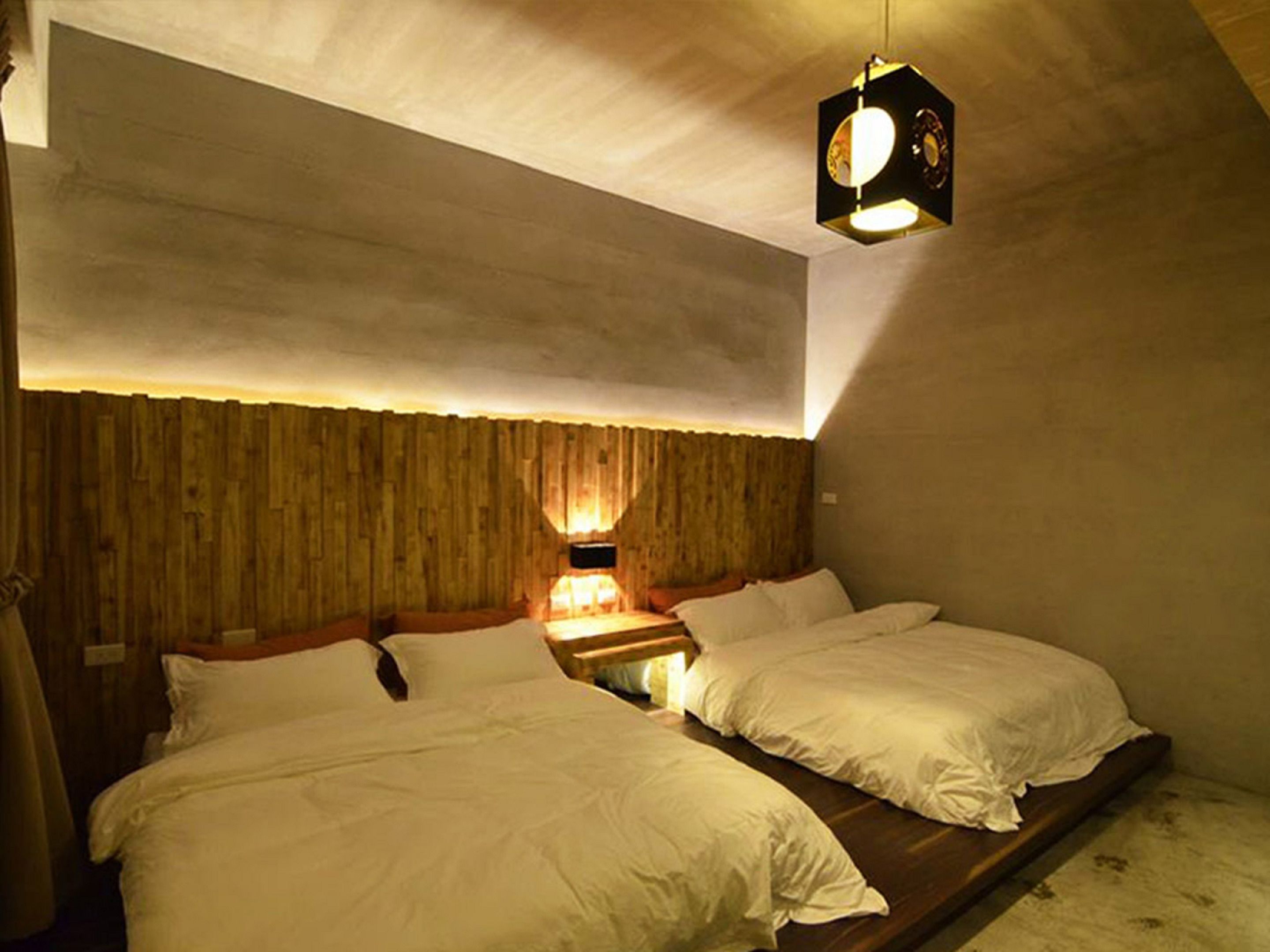 Een kamer met twee bedden, een houten hoofdbord en een hanglamp.