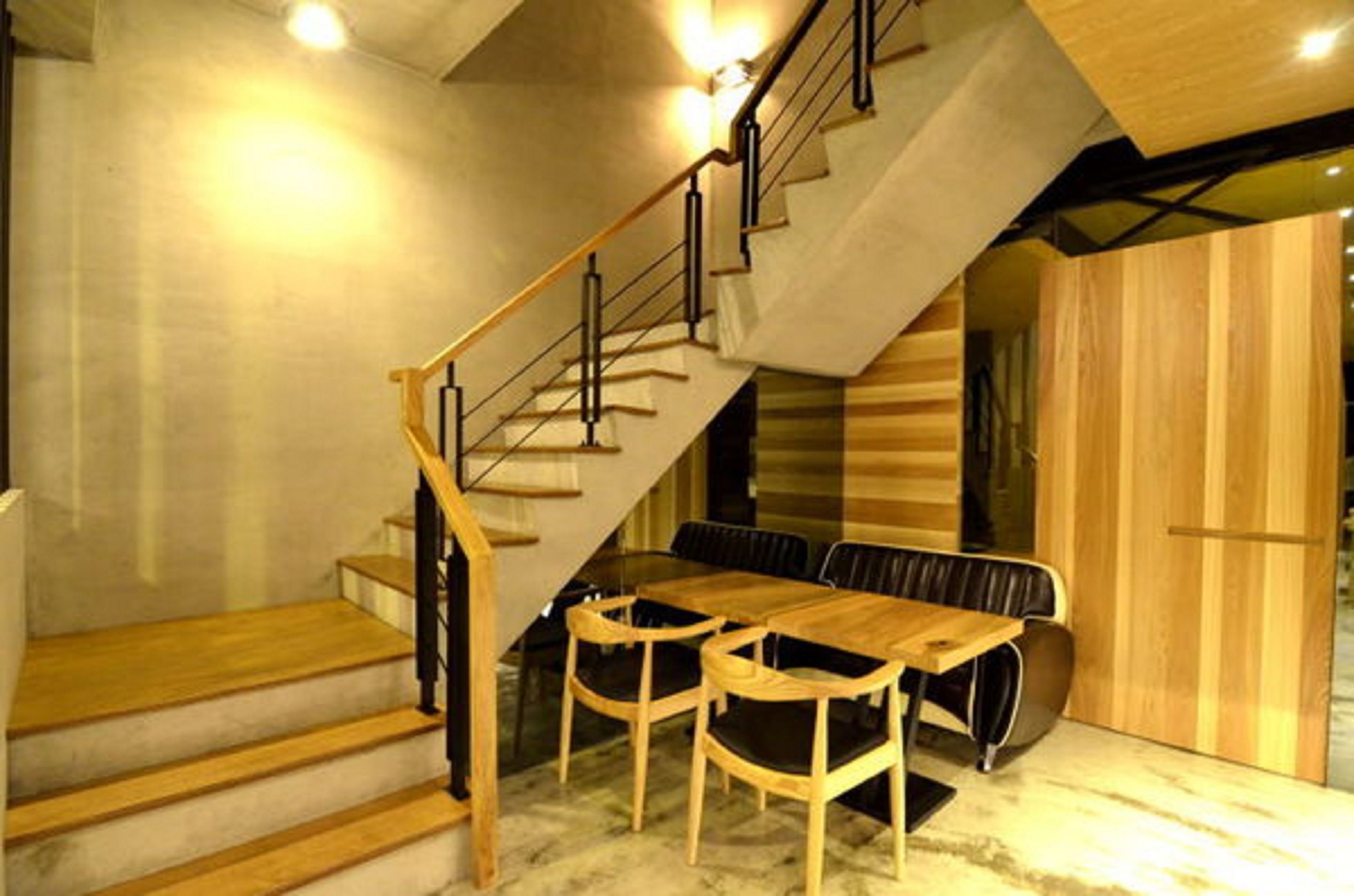 Un escalier menant à une salle à manger avec une table et des chaises en bois.