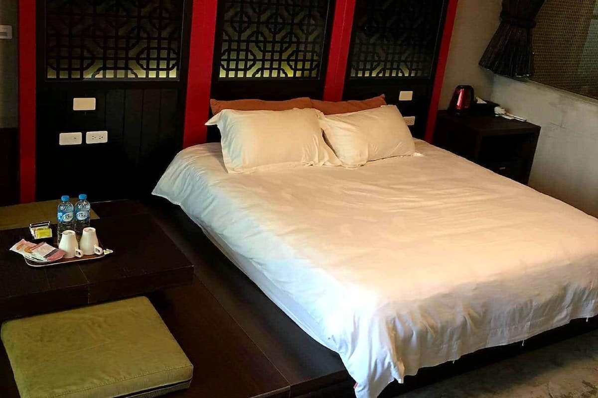Una habitación de hotel con una cama, una mesita con un set de artículos de aseo y un banco.