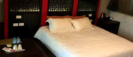 A hotel room with a bed, a small table with a tray of toiletries, and a bench.