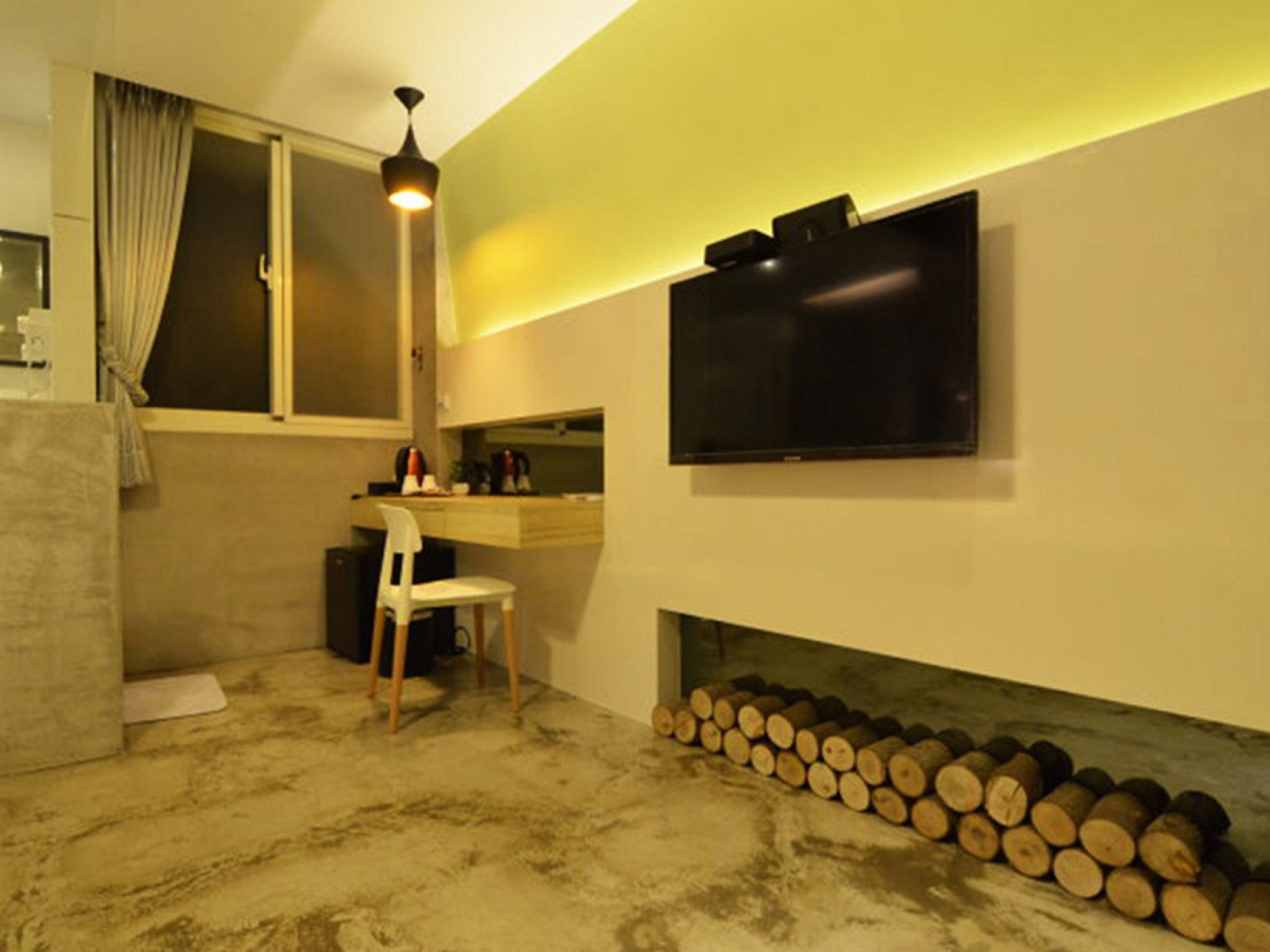 Una habitación con escritorio, silla, televisión y chimenea con leña.