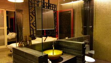Un baño moderno con mampara de vidrio, un espejo grande, un lavabo amarillo y un inodoro.