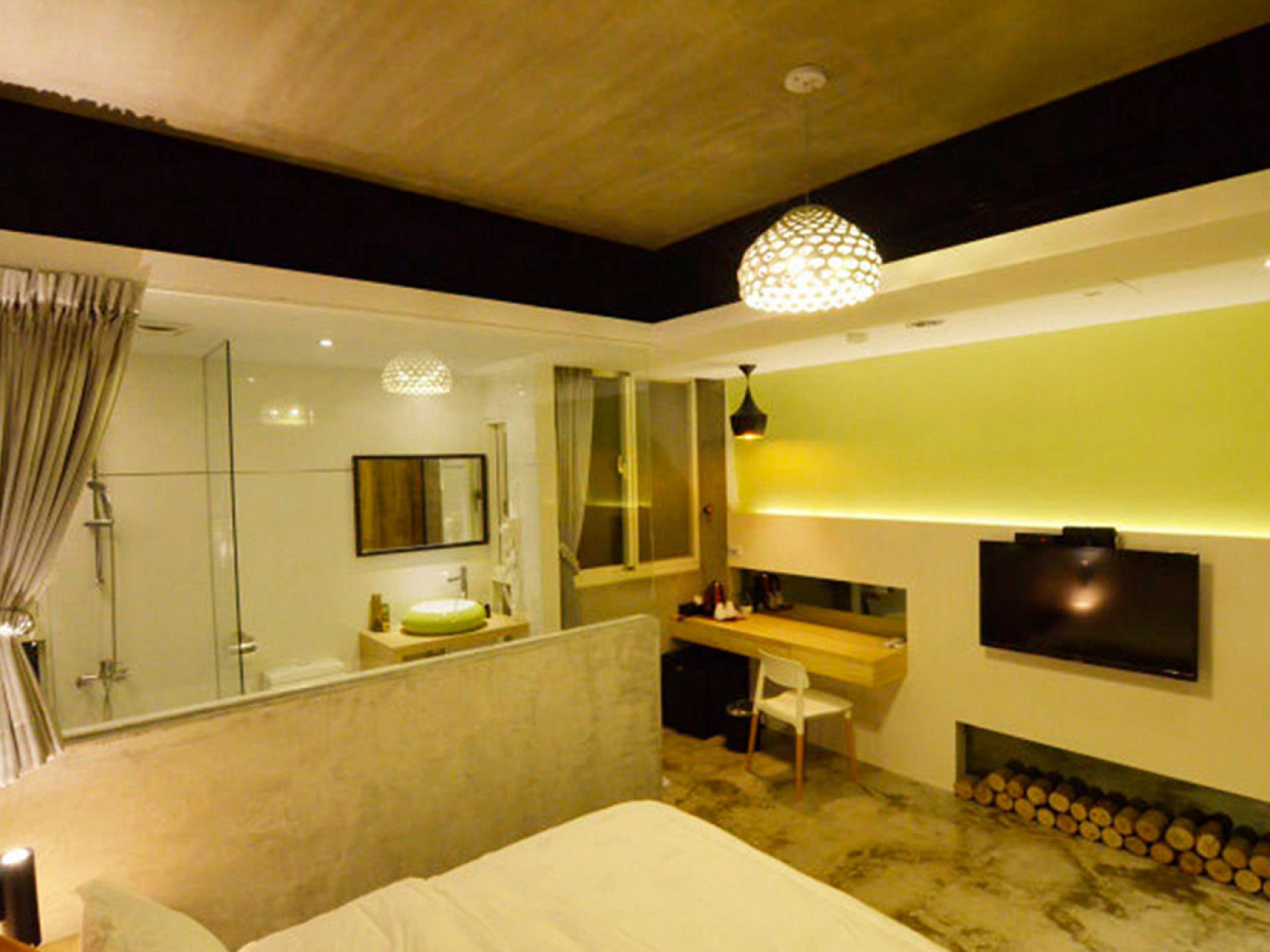 A modern bedroom with a large bed, a desk, a mirror, and a TV.