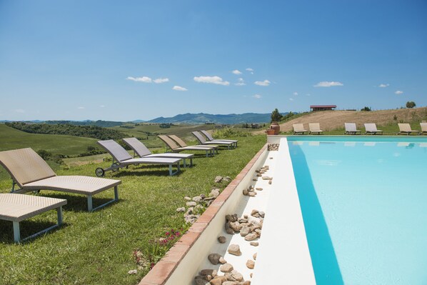 A pool area with lounge chairs and a view of rolling hills. - Agriturismo Pompilia (Volterra)