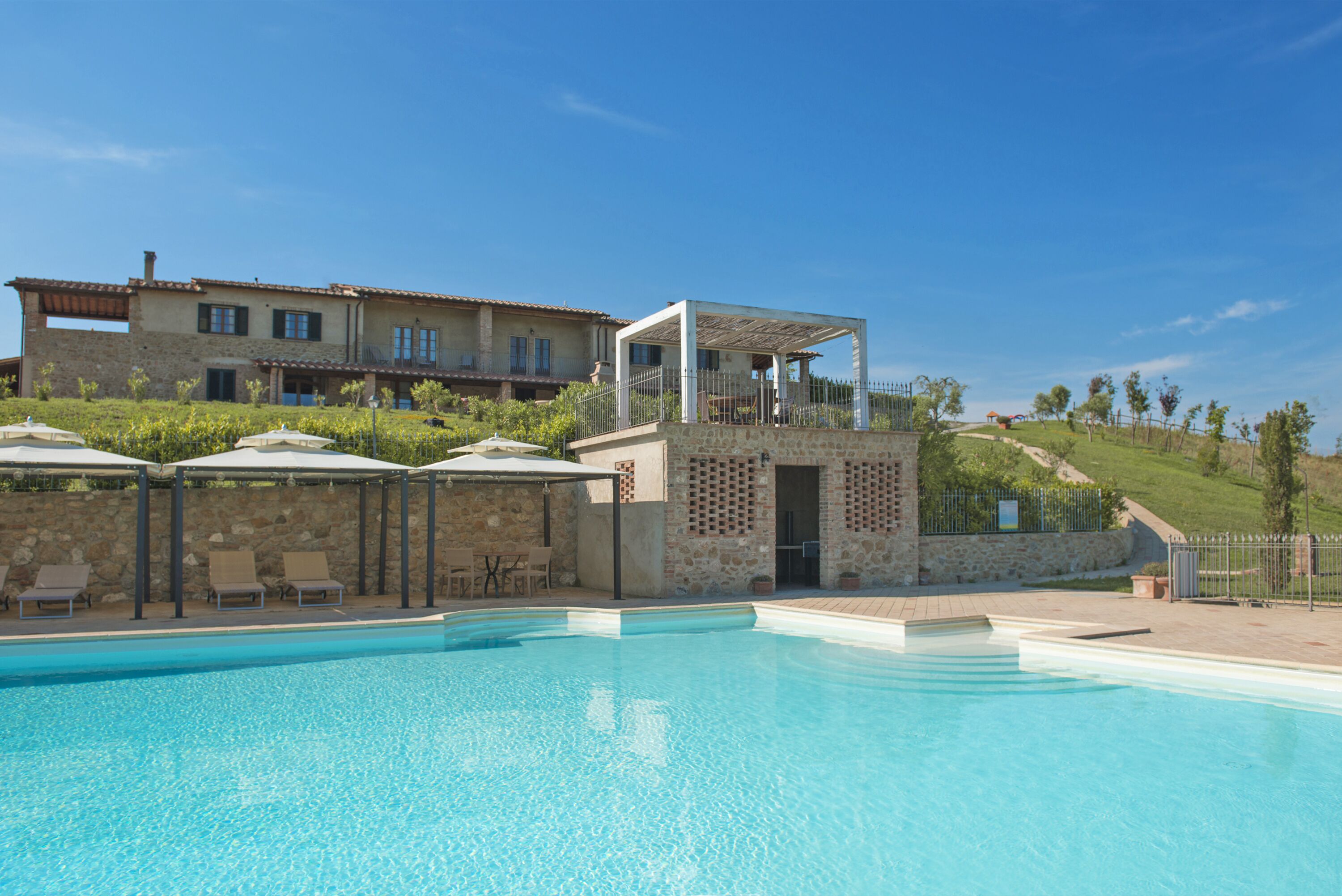 Una piscina al aire libre, sombrillas, sillones reclinables de piscina